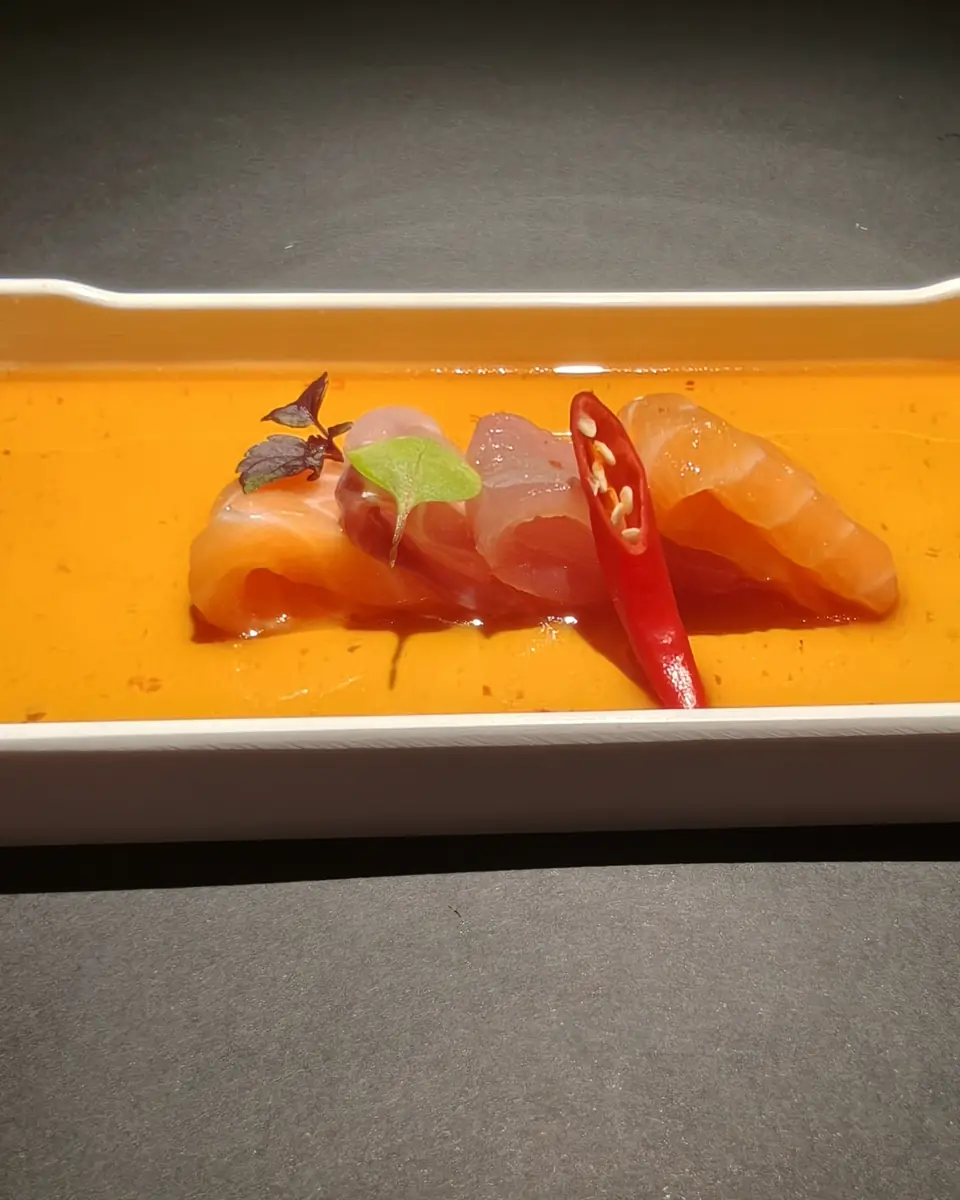 Salmon and white fish carpaccio in orange sauce, on a rectangular tray
