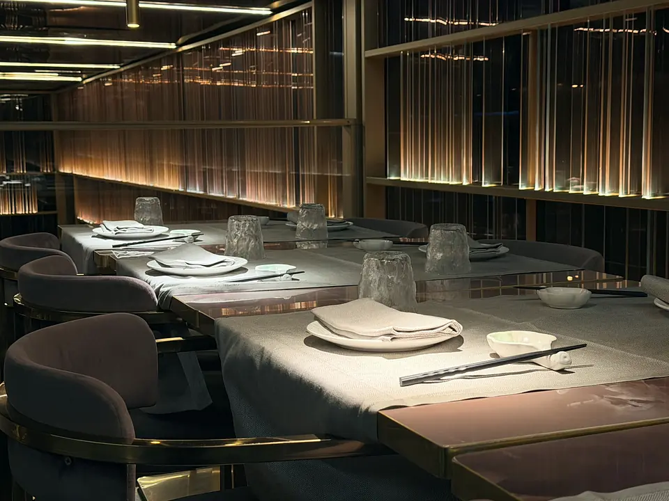 Tables set with glasses and chopsticks under the dining room's golden lights
